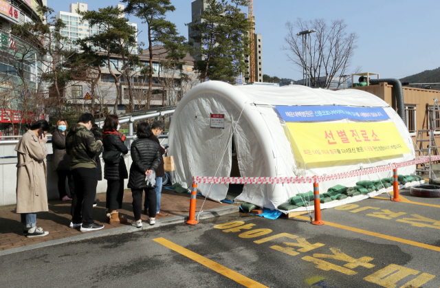 22일 부산 해운대백병원 선별진료소에서 방문객들이 코로나19 검사를 받기 위해 줄지어 기다리고 있다. 연합뉴스
