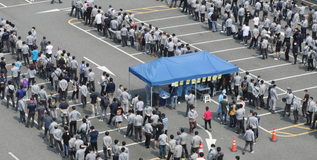현대중공업 직원과 가족 등이 잇따라 신종 코로나바이러스 감염증(코로나19) 확진 판정을 받은 가운데 지난 9일 울산 동구보건소 선별진료소에 현대중 직원들이 검사를 받기 위해 줄을 서 있다. 연합뉴스