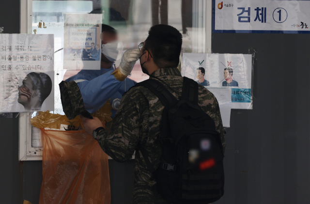 지난 20일 오전 한 시민이 서울 중구 서울역 선별검사소에서 검체를 채취하고 있다. 연합뉴스