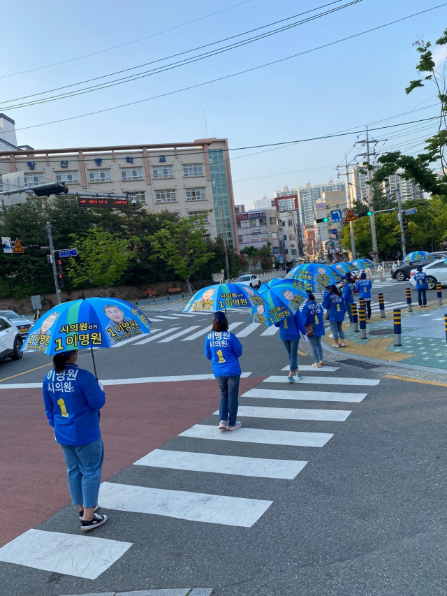 선거운동용 양산을 쓴 채 거리유세를 하는 더불어민주당 이명원 시의원 후보 선거운동원. 이명원 후보 캠프 제공