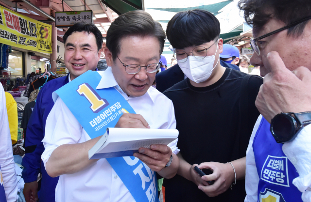 더불어민주당 이재명 총괄선대위원장이 31일 인천 모래내시장을 방문해 한 시민에게 사인을 해주고 있다.국회사진기자단