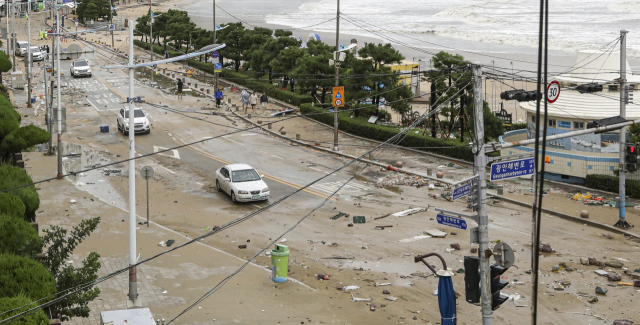 제11호 태풍 힌남노가 상륙한 6일 오전 부산 수영구 광안리해수욕장 일대 도로가 파도에 쓸려온 모래와 돌, 부유물들로 뒤덮여 있다.