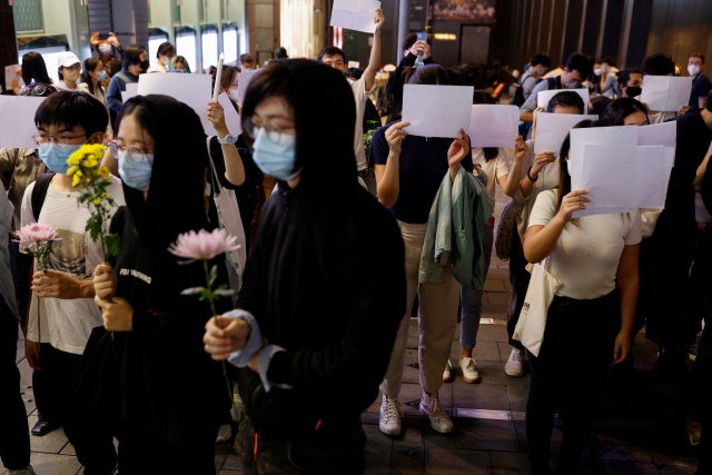 28일(현지시간) 홍콩에서 열린 중국 우루무치 화재참사 희생자 추모집회에서 시민들이 중국 정부의 ‘제로 코로나’ 정책에 반대하는 의미로 백지를 들고 있다. 2020년 시행된 국가보안법으로 홍콩에서는 시위와 집회가 금지됐지만, 시민들은 봉쇄 반대 시위 나섰다. 연합뉴스