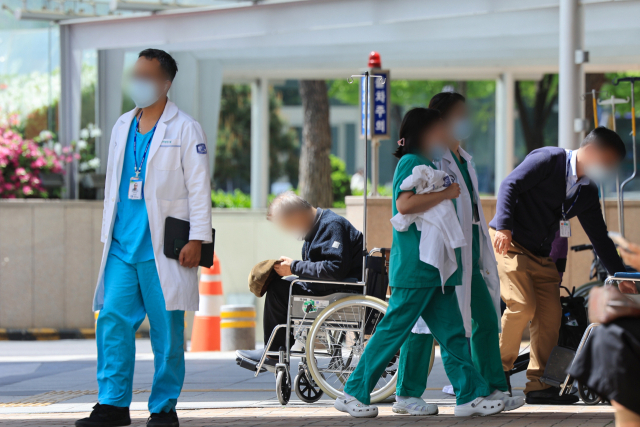 정부의 의대 증원 추진에 반발한 전공의들이 병원을 떠난 지 60일째인 18일 서울 시내 한 대학병원에서 의료진이 이동하고 있다. 연합뉴스