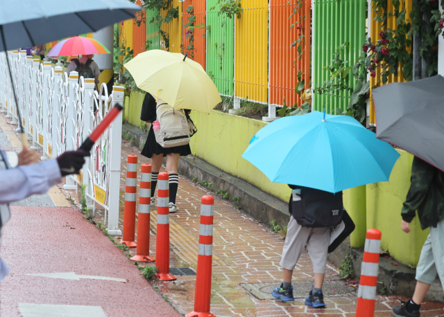 제주도에 장마가 시작된 20일 오전 제주시 노형초등학교 통학로가 우산을 든 어린이들로 붐비고 있다. 연합뉴스