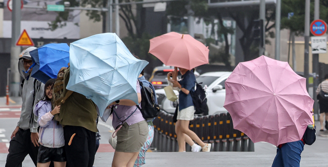 많은 비와 강한 바람을 동반한 장맛비가 거세게 내린 30일 부산 해운대구 중동 한 건널목에서 시민들이 우산을 부여잡고 힘겹게 길을 걷고 있다. 김종진 기자 kjj1761@