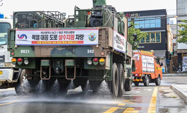 6일 오후 부산 남구 일대에서 해군작전사령부 K-10 제독차와 산악용 소방차가 아스팔트 열기를 식히기 위해 살수차로 운용되고 있다. 부산 남구는 다음달 13일까지 해군작전사령부 장비 3대와 인력을 지원 받아 폭염 대응 살수차로 운영한다. 김종진 기자 kjj1761@