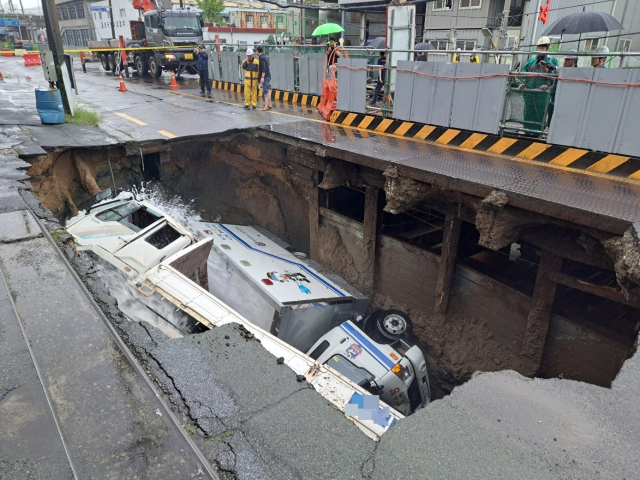 21일 오전 부산 사상구의 한 도로에서 싱크홀이 발생해 대형 차량이 빠지는 사고가 발생했다. 부산소방재난본부 제공