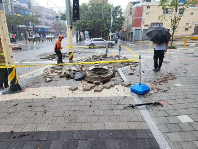 21일 오전 부산 부산진구의 한 맨홀에서 물이 역류해 아스팔트 블럭이 파손됐다. 부산소방재난본부 제공