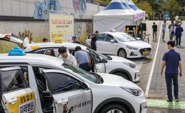 부산시와 택시운송사업조합이 처음으로 ‘법인택시 운수종사자 채용박람회’를 개최했다. 17일 부산 부산진구 부산시민공원을 찾은 구직자들이 택시기사 채용 홍보부스를 살펴보고 있다. 김종진 기자 kjj1761@