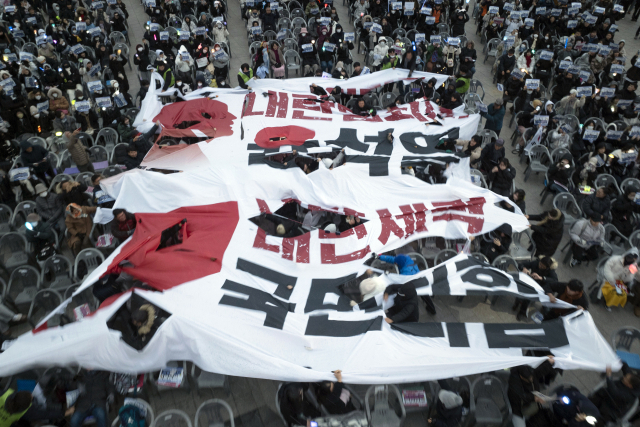 21일 광주 동구 5·18민주광장에서 열린 '윤석열 즉각 퇴진과 사회 대개혁 쟁취를 위한 7차 광주시민총궐기대회'에서 시민들이 현수막 찢기 퍼포먼스하고 있다. 연합뉴스