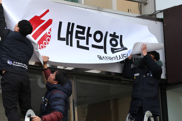 11일 오전 울산 남구 삼산동 국민의힘 울산시당 앞에서 윤석열 퇴진 울산운동본부 관계자들이 시당사 간판에 '내란의힘 울산광역시당'이라고 적힌 현수막을 붙이고 있다. 연합뉴스