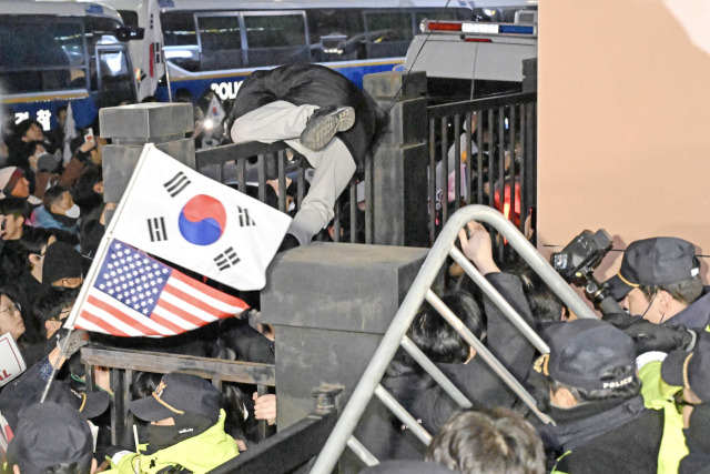 윤석열 대통령의 구속영장이 발부된 18일 오후 서울 마포구 서울서부지방법원에서 윤 대통령 지지자가 담장을 넘어 법원으로 들어가고 있다. 연합뉴스