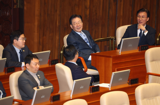 더불어민주당 이재명 대표가 11일 서울 여의도 국회에서 열린 본회의에서 국민의힘 권성동 원내대표의 교섭단체 대표 연설 도중 의원들과 웃으며 대화를 나누고 있다. 연합뉴스