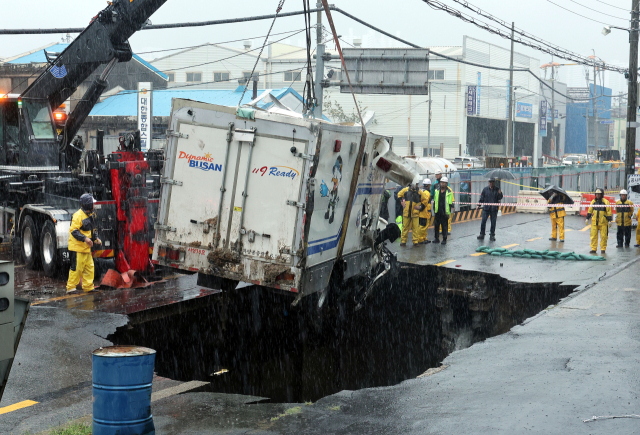 지난해 9월 21일 폭우로 부산 사상구 한 도로에 대형 싱크홀에 빠진 트럭을 현장 관계자들이 꺼내고 있다. 부산일보DB