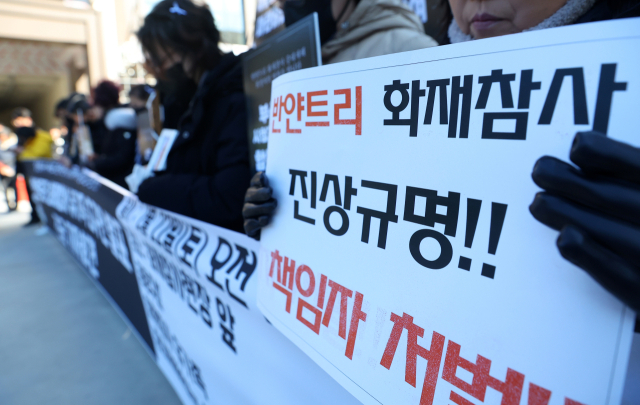 지난 22일 오전 부산 기장군 반얀트리 리조트 화재현장에서 열린 유가족 요구안 발표 기자회견에서 유가족들이 '철저한 진상규명'을 요구하는 손팻말을 들고 있다. 연합뉴스