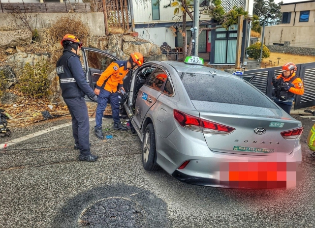 울산 울주군 서생면 진하리 한 커브길에서 택시가 벽면을 충돌 후 멈춰 서 있다. 소방당국이 사고 현장을 수습하는 모습. 울산소방본부 제공