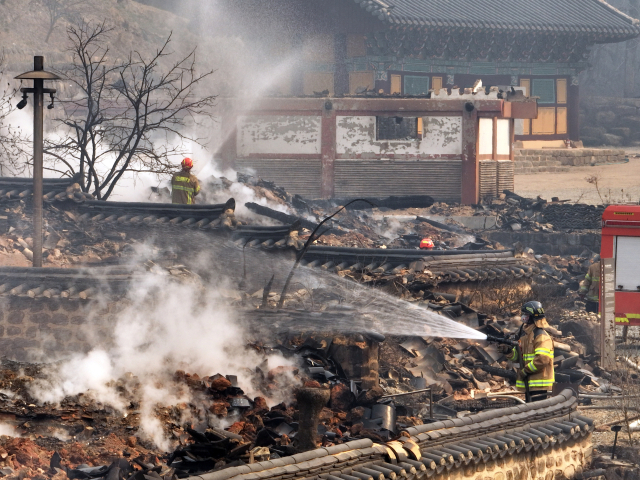 경북 의성 고운사에서 소방대원들이 불에 탄 건물 위에 물을 뿌리고 있다. 연합뉴스