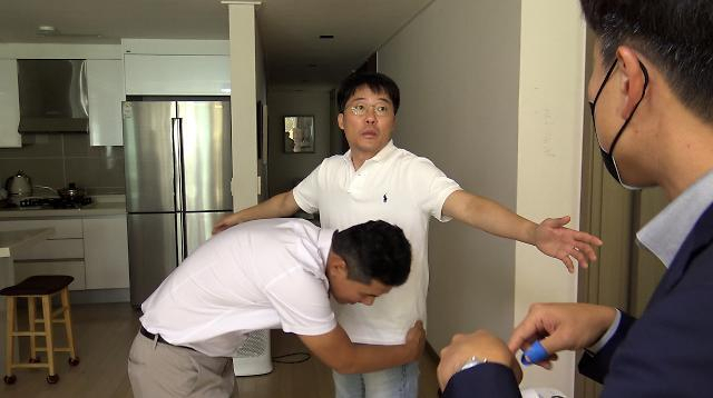 영화 ‘압수수색: 내란의 시작’ 속 한 장면. 자택 압수수색 과정에서 몸 수색을 받고 있는 뉴스타파 한상진 기자의 표정에서 황당함이 드러납니다. 영화로운형제 제공