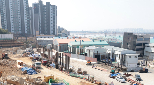 부산 사상구 엄궁동에 위치한 삼정환경산업 부지와 사상~하단선 차량기지창 공사 현장. 철제 빔을 사이에 두고 부지를 정리 중인 곳이 기지창 공사 현장이고, 인접한 일부 공장 건물들이 있는 곳이 현재의 삼정환경산업 부지다. 기지창 공사로 삼정환경산업은 아파트와 조금 더 가까운 곳으로 이전을 추진 중이다. 정대현 기자 jhyun@
