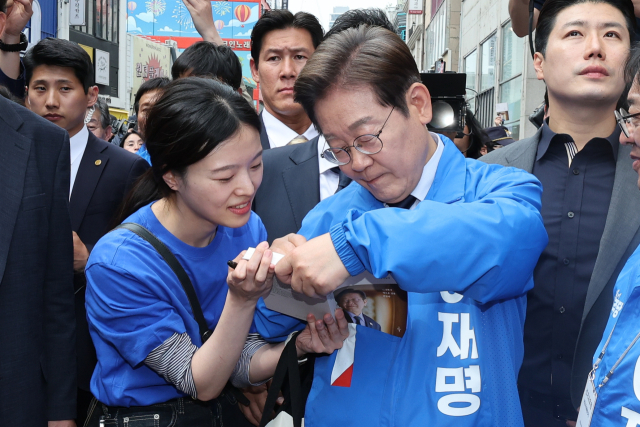 더불어민주당 이재명 대선 후보가 13일 '보수의 심장'이라고 불리는 대구광역시의 동성로 거리에서 집중 유세를 마친 후 여성당원 김희정 씨에게 사인을 해주고 있다. 연합뉴스