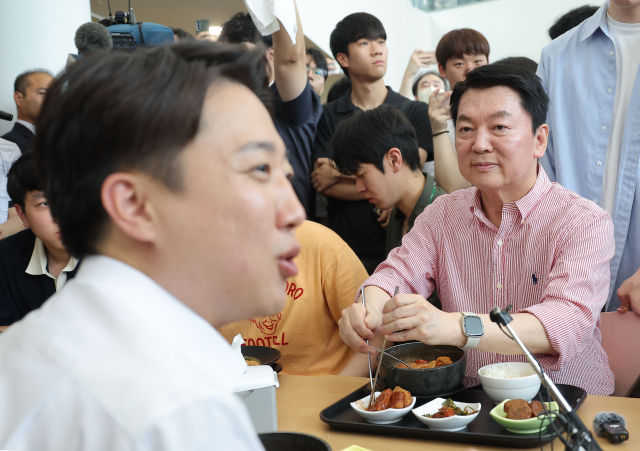 국민의힘 안철수 의원이 21일 경기 성남시 가천대학교 글로벌캠퍼스에서 열린 '학식 먹자 이준석' 행사에 참석한 가운데 학생들과 대화를 나누는 개혁신당 이준석 대선 후보를 바라보고 있다. 연합뉴스