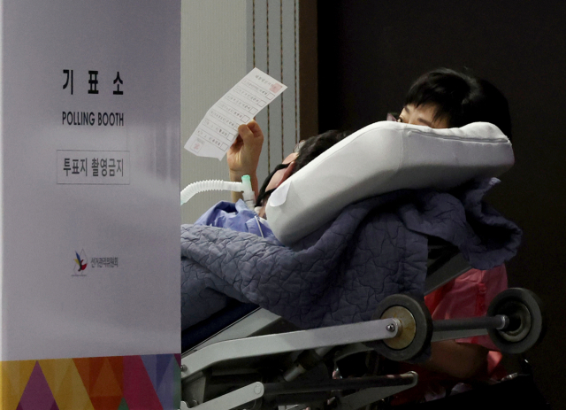 제21대 대통령선거일인 3일 서울 용산구 중부기술교육원에 마련된 한남동 제3투표소에서 한 환자가 보호자 도움을 받아 투표에 참여하고 있다. 연합뉴스