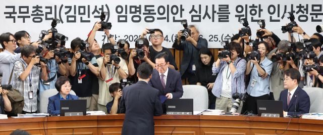 김민석 국무총리 후보자가 24일 서울 여의도 국회에서 열린 인사청문회에서 총리 후보자 인사청문특별위원회 위원장인 국민의힘 이종배 의원에게 선서문을 제출하고 있다. 연합뉴스