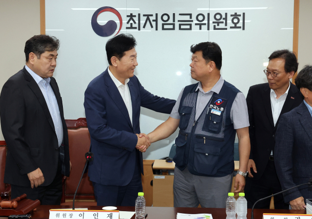 최저임금위원회 사용자위원 운영위원인 류기정 한국경영자총협회 전무(왼쪽)와 근로자위원 운영위원인 류기섭 한국노총 사무총장이 10일 정부세종청사에서 열린 제12차 전원회의에서 내년 최저임금을 시간당 1만320원으로 17년 만에 합의로 결정한 뒤 악수하고 있다. 왼쪽은 이인재 위원장, 오른쪽은 이명로 중소기업중앙회 인력정책본부장. 연합뉴스