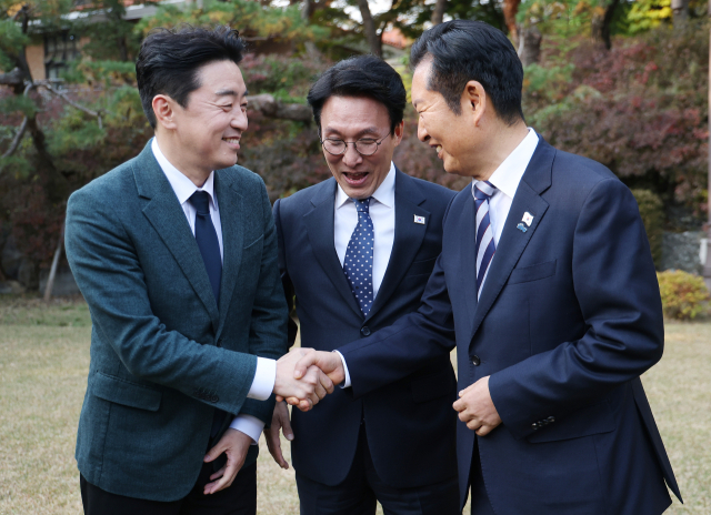 김민석 국무총리(가운데)가 9일 서울 종로구 총리공관에서 열린 고위당정협의회에서 강훈식 대통령 비서실장(왼쪽), 더불어민주당 정청래 대표와 손을 잡고 있다. 연합뉴스