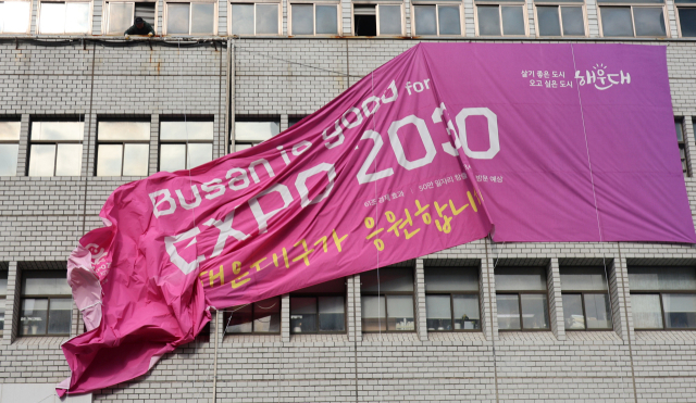 2023년 11월 부산 해운대구청사 외벽에 걸려있던 2030부산세계박람회 유치 응원 현수막이 철거되는 모습. 작은 사진은 '2030부산세계박람회 유치 활동 백서' 표지. 연합뉴스·부산시 제공