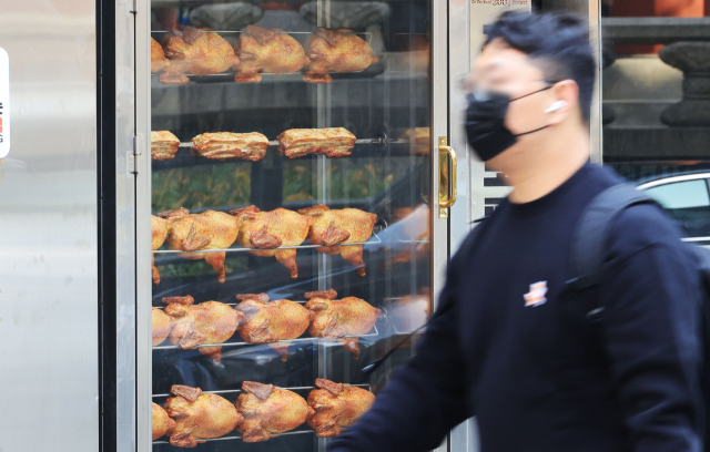 치킨 ‘조리전 중량’ 표시 의무제가 10대 치킨 프랜차이즈에 도입된다. 서울 종로에서 시민이 치킨집 앞을 지나고 있는 모습. 연합뉴스