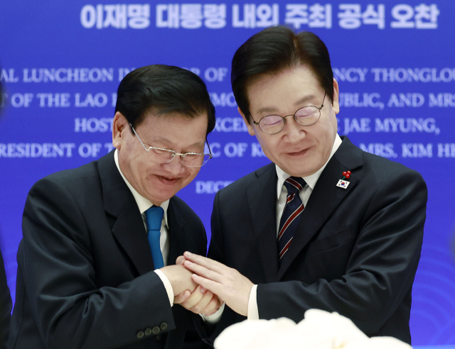 이재명 대통령이 15일 용산 대통령실에서 열린 한-라오스 공식오찬에서 통룬 시술릿 라오스 국가주석과 건배 후 손을 맞잡고 있다. 연합뉴스