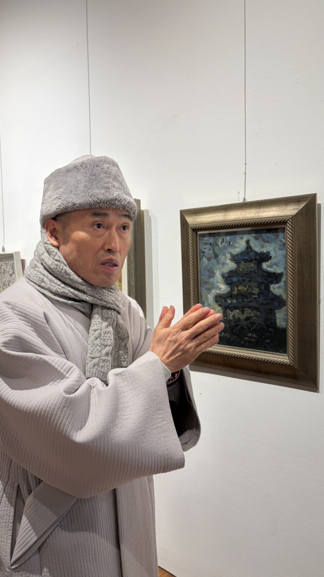 금정총림 범어사 정오 주지 스님이 '범어사 가는 길'을 그린 윤종철 작가 작품 앞에서 범어사 굴뚝을 설명하고 있다. 김은영 기자 key66@