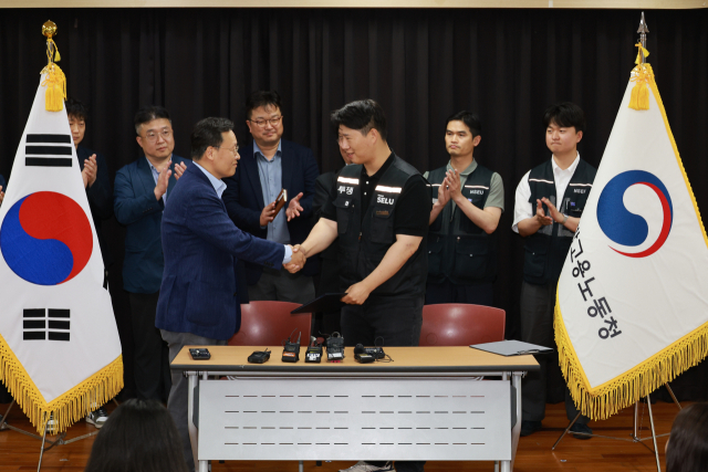 20일 경기도 수원시 장안구 경기고용노동청에서 열린 삼성전자 임금협상을 마친 후 여명구 삼성전자 DS(디바이스솔루션·반도체 사업 담당) 피플팀장과 최승호 삼성그룹 초기업노동조합 삼성전자지부 위원장이 잠정 합의안에 서명한 후 손을 맞잡고 있다. 연합뉴스