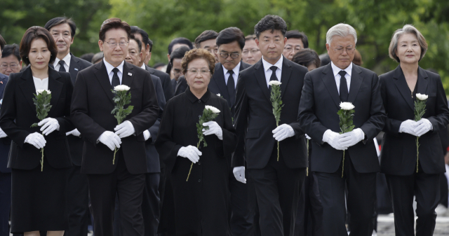 이재명 대통령 부부, 권양숙 여사와 장남 건호 씨, 문재인 전 대통령 부부가 23일 경남 김해 봉하마을에서 열린 고 노무현 전 대통령 서거 17주기 추도식에서 국화를 들고 헌화대로 향하고 있다. 연합뉴스