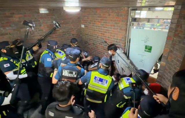 지난 5일 서울 송파구 잠실7동 제2 투표소에 모여든 시위대를 경찰이 해산하는 과정에서 한 시위 참가자가 양손을 들어 보이며 