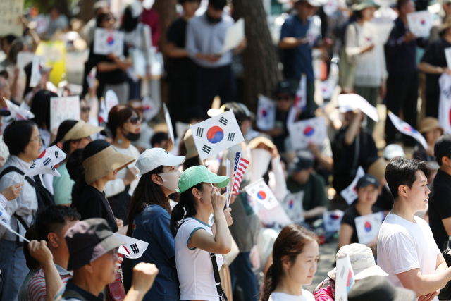 6·3 지방선거 투표용지 부족 사태를 규탄하며 재선거를 요구하는 '잠실 개표소 봉쇄 시위'가 계속되고 있는 9일 서울 송파구 올림픽공원 핸드볼경기장에서 한 참가자가 태극기를 흔들고 있다. 연합뉴스