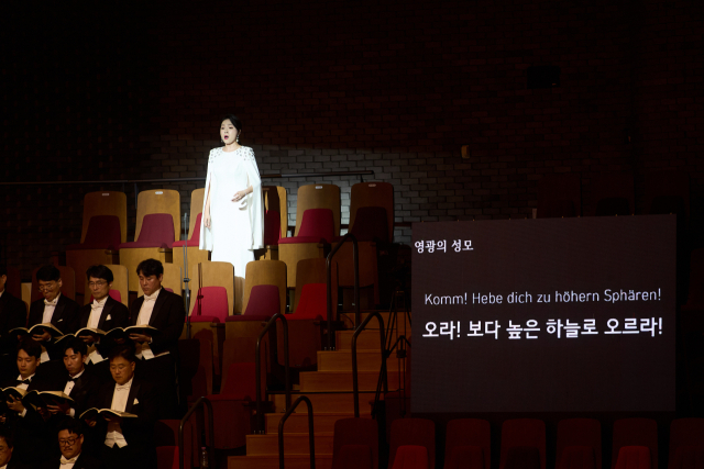 지난 18일 오후 부산콘서트홀에서 열린 부산시립교향악단 제631회 정기연주회 ‘부산, 말러’ 공연 모습. 영광의 성모 역을 맡은 소프라노 박하나가 합창석 뒤 객석에서 노래를 부르고 있다. 부산시향 제공