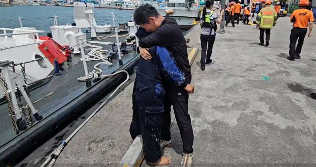 25일 부산 기장군 앞바다 선박 충돌 사고로 침몰한 어선에서 구조된 승선원이 육지에 무사히 도착한 뒤 지인으로 보이는 이와 부둥켜안고 오열하고 있다. 울산해경 제공