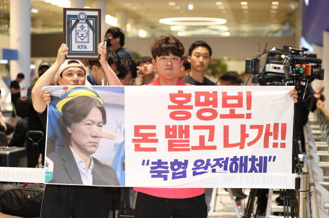 2026 북중미 월드컵에서 최악의 성적을 낸 한국 축구 국가대표팀 입국장에서 팬들이 현수막을 들고 항의를 표시하고 있다.연합뉴스