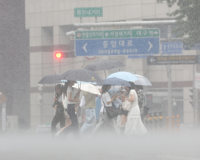 17일 대구 중구 동성로에서 시민들이 우산을 쓰고 쏟아지는 장맛비를 피하며 이동하고 있다. 연합뉴스