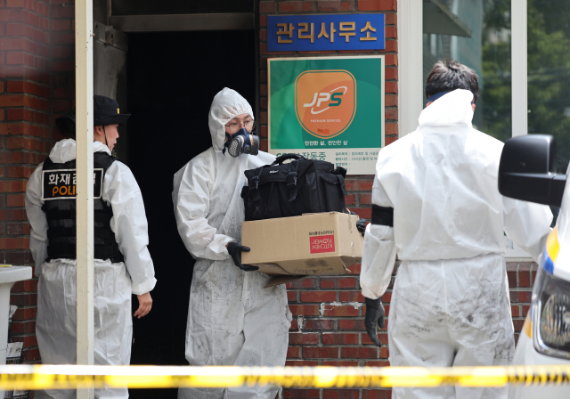 지난달 23일 오전 8시 29분께 경북 경산시 사동 한 아파트 관리실 안에서 폭발 추정 사고가 난 가운데 경찰 과학수사대가 증거물로 보이는 물건을 담은 종이상자를 가지고 철수하고 있다. 연합뉴스