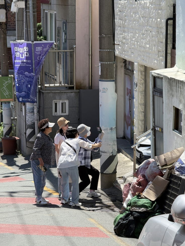 ‘아미동 사진가’ 어르신들이 지난여름 골목길을 돌아보며 휴대전화로 마을 풍경을 담고 있다. 부산문화재단 제공