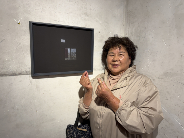 “이건 제 작품이에요!” 75세의 이경자 어르신이 뿌듯한 표정으로 전시된 자신의 사진 앞에서 포즈를 취하고 있다. 강성규 사진가 제공