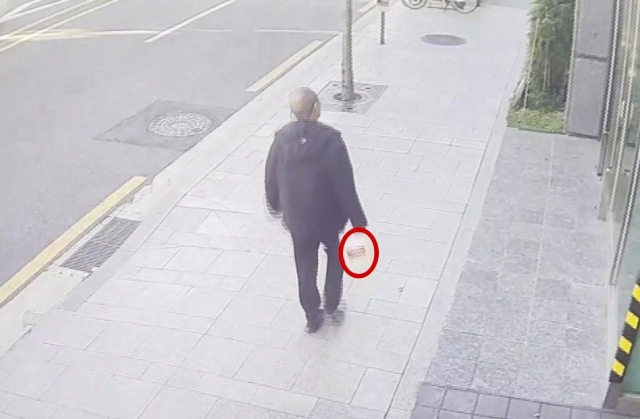 20일 방화 혐의로 체포된 70대 남성 A 씨가 화재 발생 전 인화 물질로 추정되는 물건을 들고 서울 강남구 역삼동의 한 건물을 향해 이동하는 모습. 연합뉴스