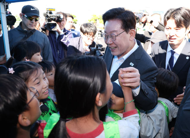 이재명 대통령이 지난 22일 전북 익산 왕궁초등학교에서 열린 가을 체육한마당에서 학생들과 인사하고 있다. 연합뉴스