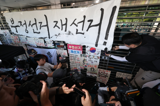6·3 지방선거 투표용지 부족 사태로 촉발된 잠실 개표소 봉쇄 시위가 이어진 9월 8일 서울 송파구 올림픽공원 핸드볼경기장에서 경찰이 진입을 위해 '부정선거 재선거'라는 문구가 적힌 종이를 제거하고 있다. 연합뉴스