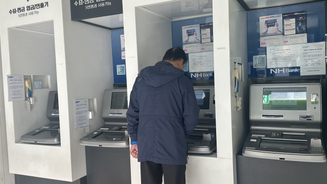 27일 오전 부산 사하구 하단동의 한 은행 현금자동입출금기(ATM)에서 시민이 현금을 입출금하고 있다. 이예슬·손희문 기자 ys@